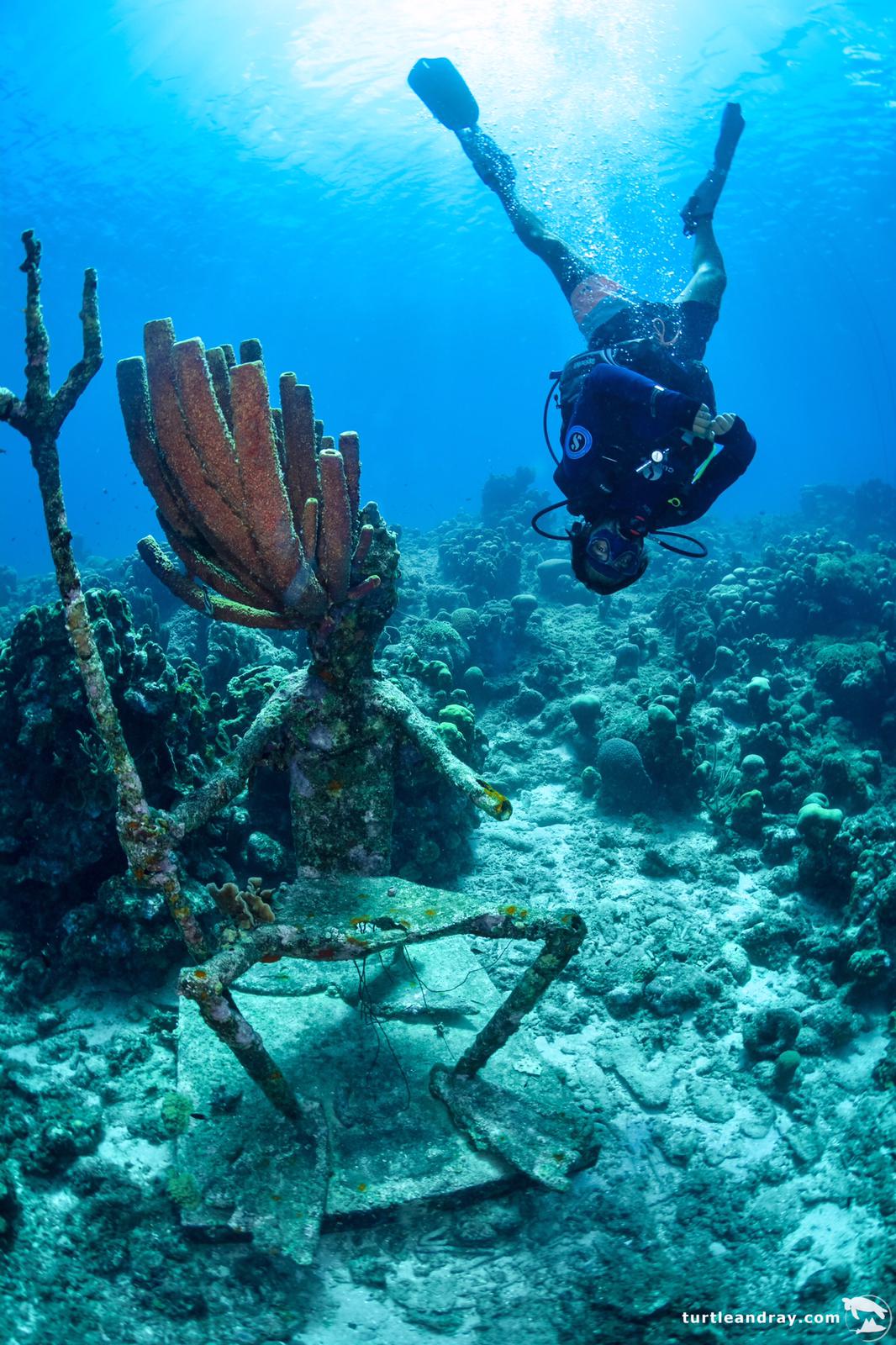 Diver upside down standing next to Poseidon statue